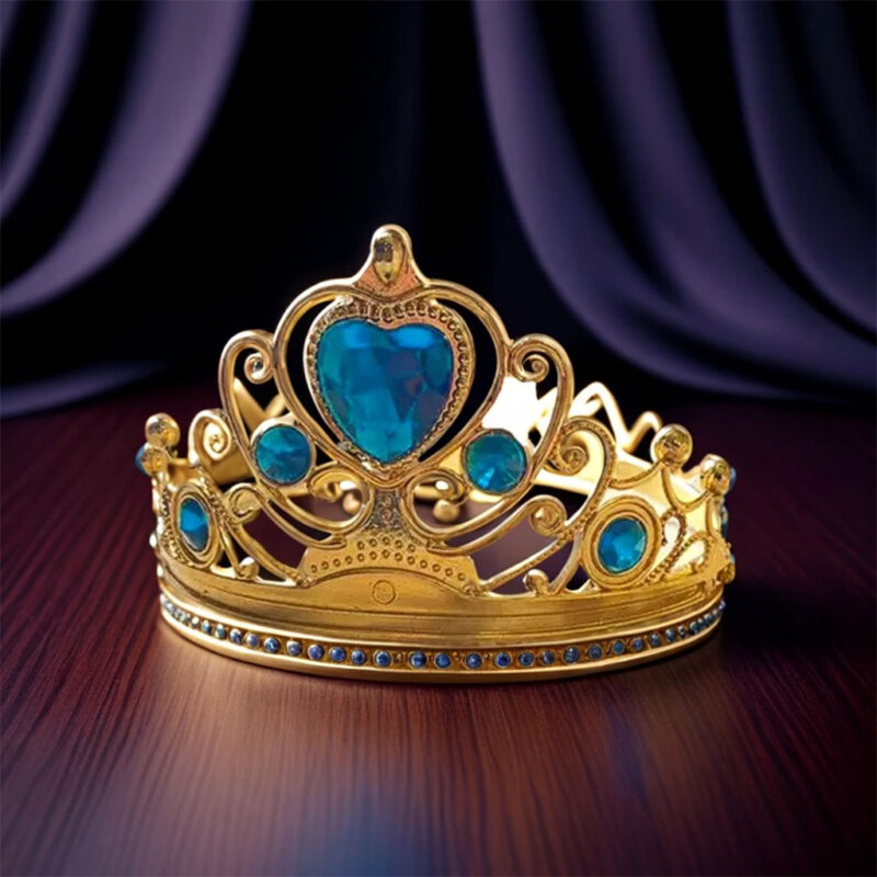 A sparkling Gold Princess Crown with a large blue heart-shaped gemstone and smaller blue and clear jewels, resting on a polished wooden surface.