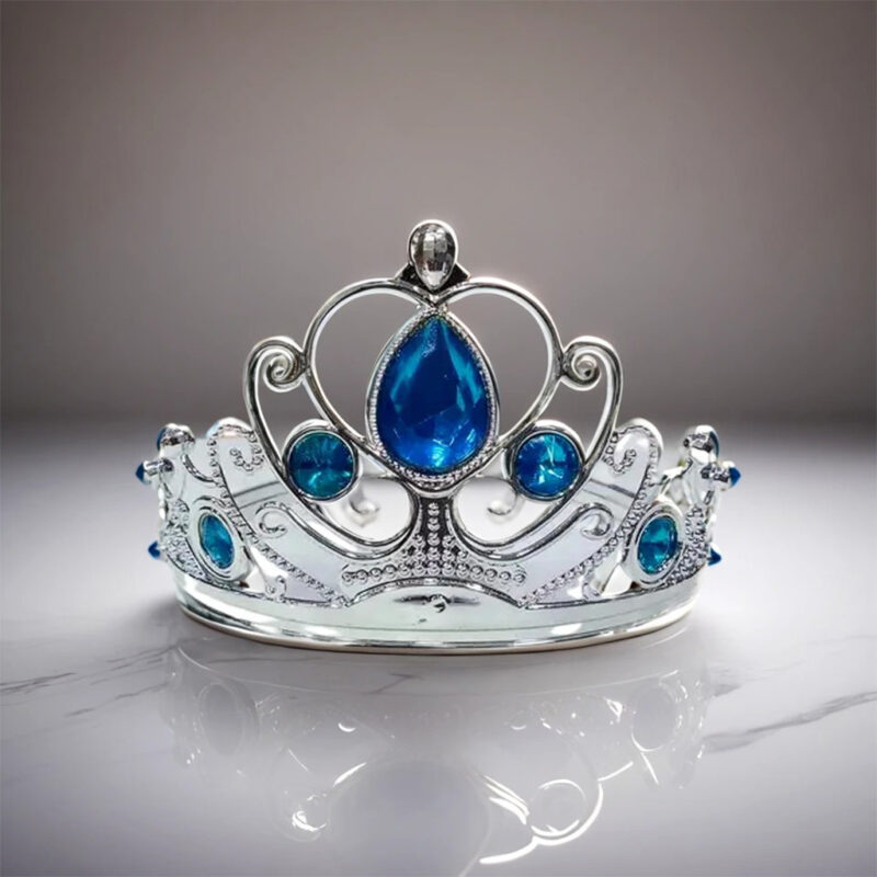 A sparkling Silver Princess Crown with blue and clear gemstones, resting on a surface.