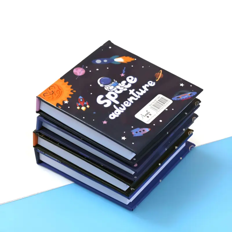 A stack of black Space Mini Notebooks with "Space adventure" on the top cover, featuring an astronaut, rockets, and planets, on a white and blue surface.