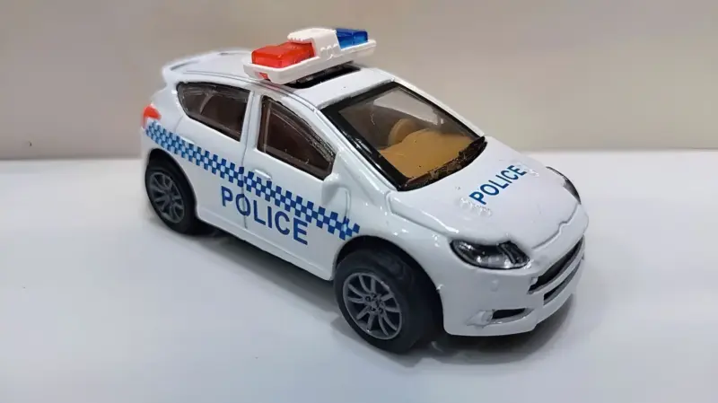A white and blue Metal Police Car Toy with "POLICE" written on the side, featuring a siren light bar on top, viewed from the front-side.